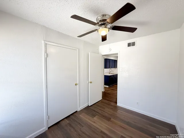 an empty room with wooden floor ceiling fan and a ceiling fan