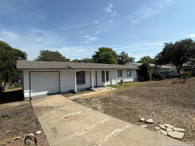 a front view of house with yard and trees in the background