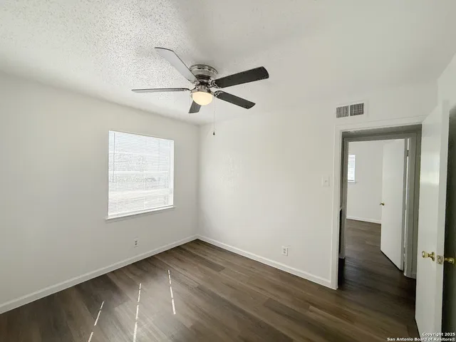 a view of a room with wooden floor and a ceiling fan