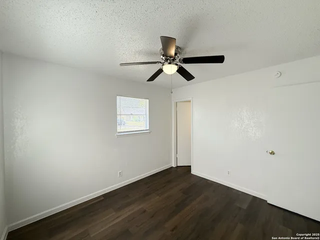 a view of a room with wooden floor and a ceiling fan