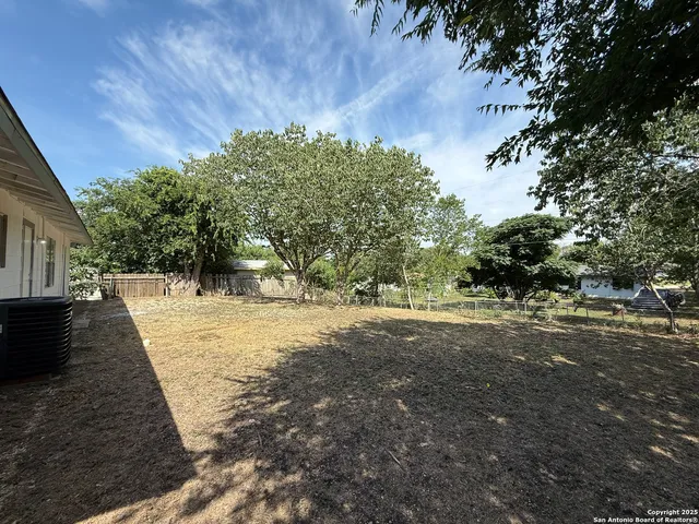 a view of a yard in front of a house with large trees