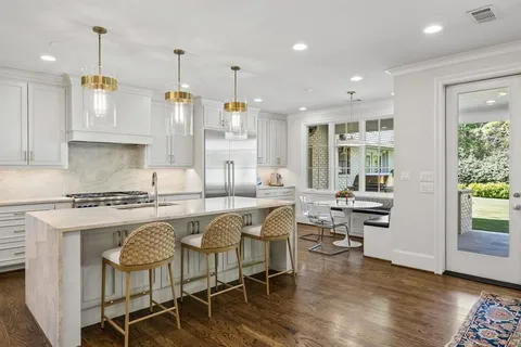 a kitchen with stainless steel appliances granite countertop a stove top oven a refrigerator a sink and white cabinets with wooden floor