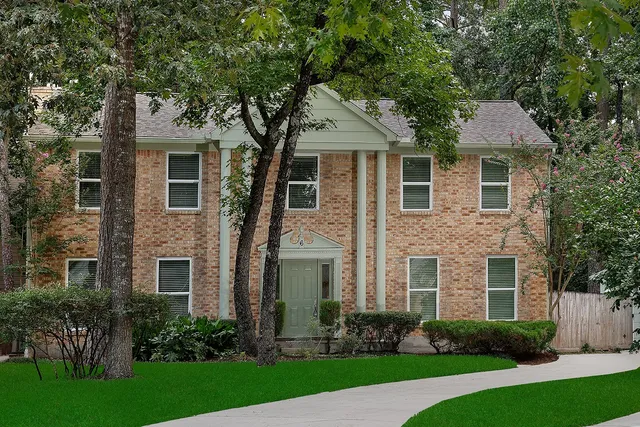 a front view of a house with a yard and trees