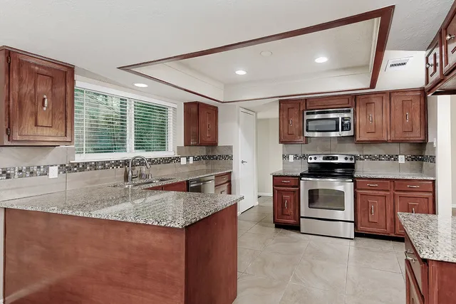 a kitchen with stainless steel appliances granite countertop a stove sink microwave and refrigerator