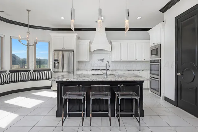 a kitchen with kitchen island granite countertop a table chairs sink and cabinets
