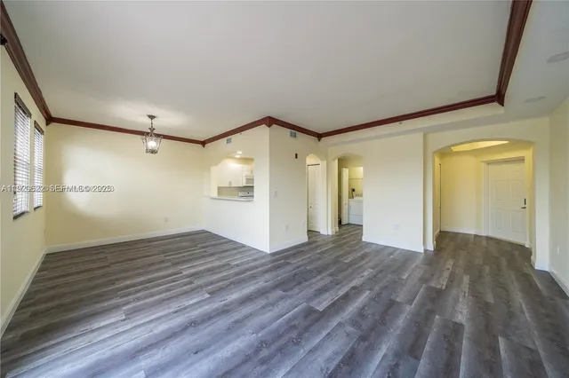 a view of empty room with wooden floor and windows