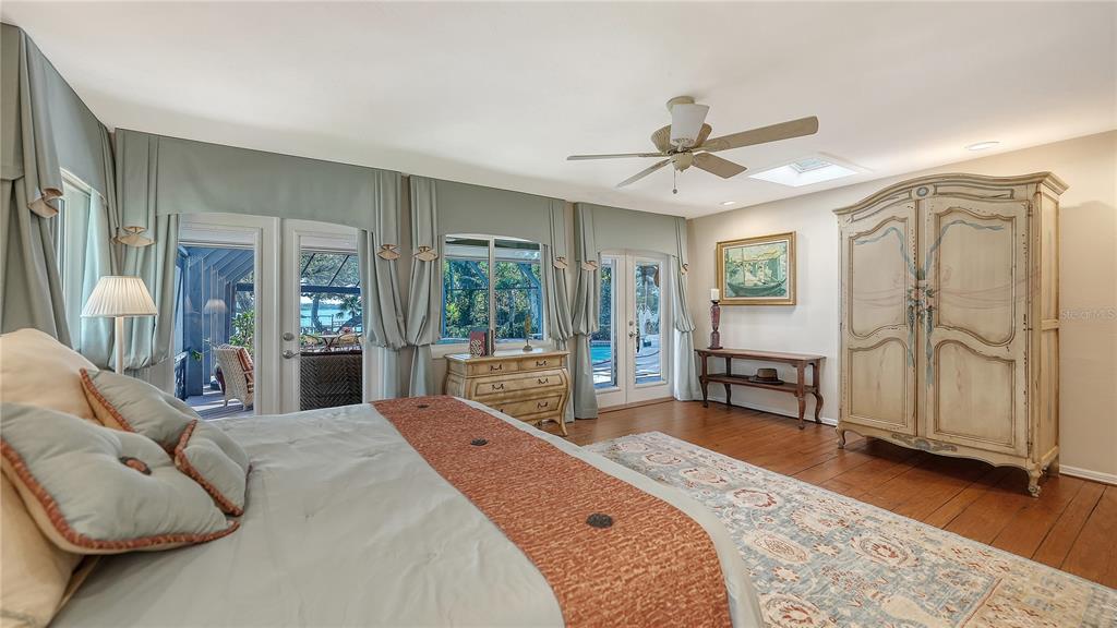 1042 North Casey Key Road Nokomis, FL 34275 - Photo 29 of 77 a spacious bedroom with a bed a chandelier and large window