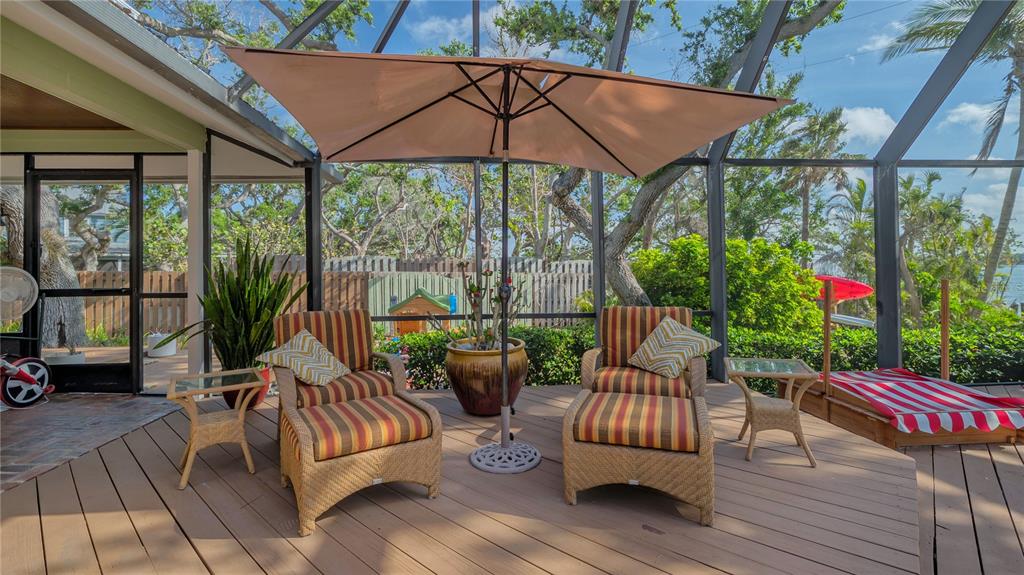 1042 North Casey Key Road Nokomis, FL 34275 - Photo 51 of 77 a view of a patio with couches and table and chairs under an umbrella