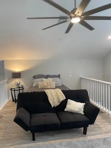 a bedroom with a bed couch and a ceiling fan