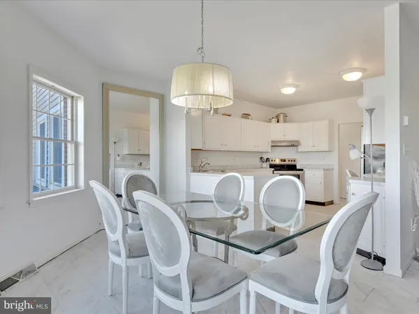 a kitchen with stainless steel appliances granite countertop a dining table chairs and a refrigerator