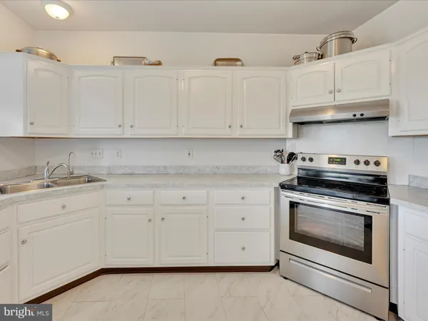 a kitchen with granite countertop white cabinets and stainless steel appliances