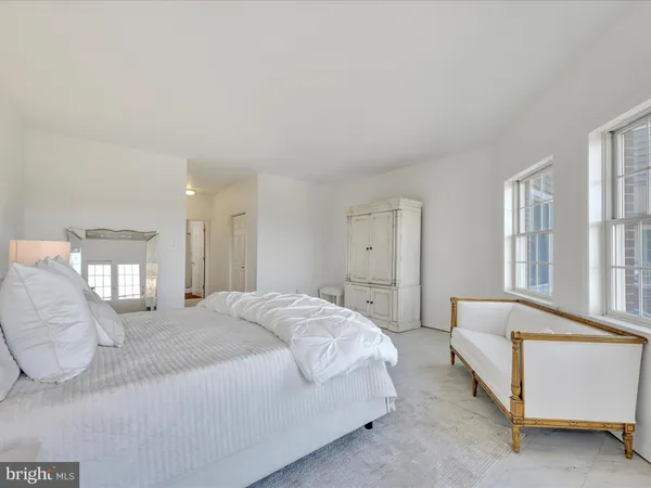 a spacious bedroom with a bed a couch and windows