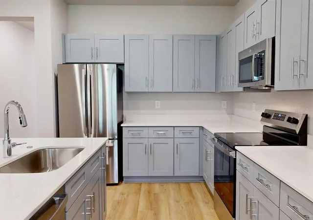 a kitchen with stainless steel appliances granite countertop a sink a stove a refrigerator and a microwave