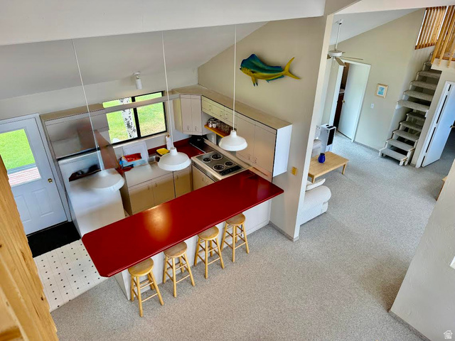 1825 North Cisco Road Laketown, UT 84038 - Photo 16 of 34 Vaulted ceiling, built-in kitchen cabinetry, red countertop island, built-in electric range, and carpeted stairs