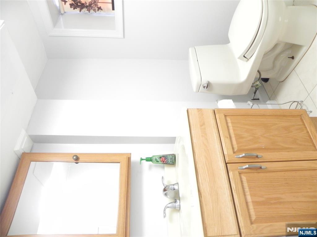 70 Christina Street Little Ferry, NJ 07643 - Photo 12 of 16 a bathroom with a toilet a sink and a mirror