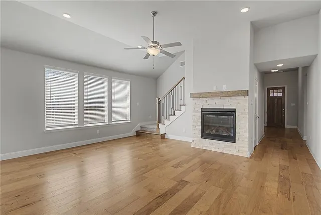 an empty room with windows fireplace and a kitchen view