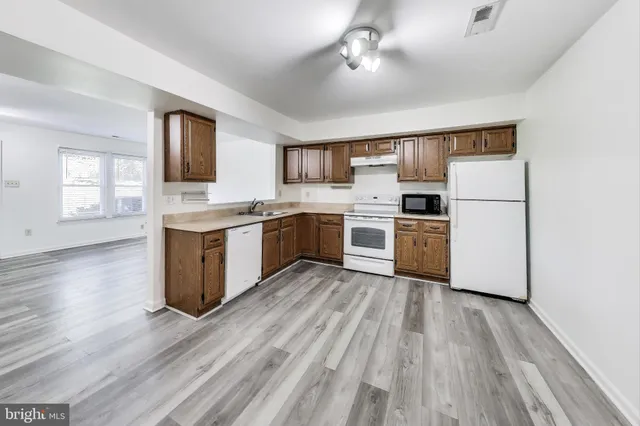 a kitchen with wooden floors and white appliances