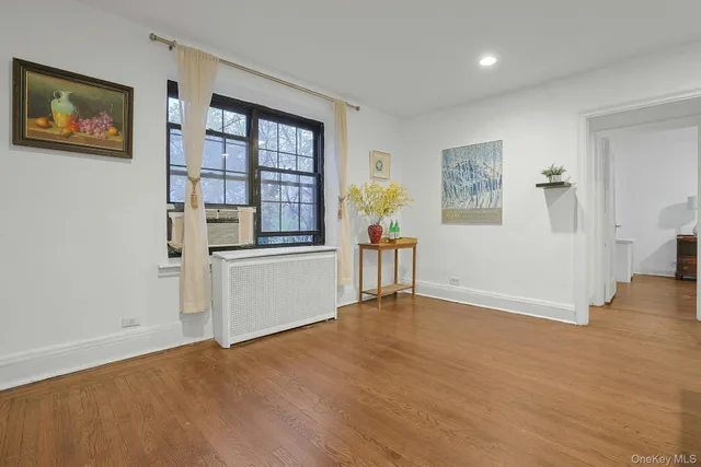 a view of an empty room with a window and wooden floor