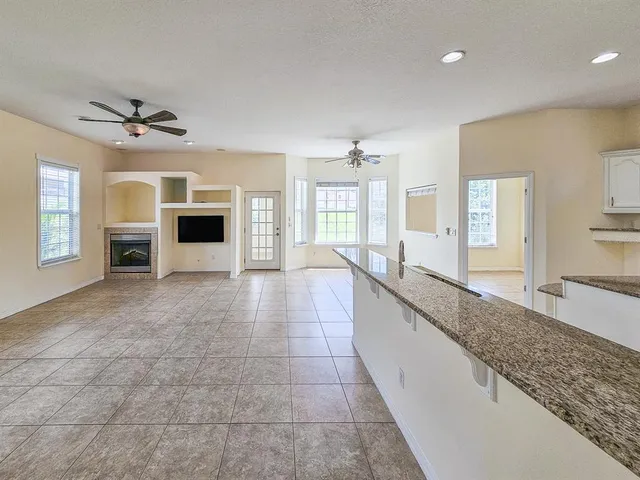 a large kitchen with granite countertop a sink and white cabinets