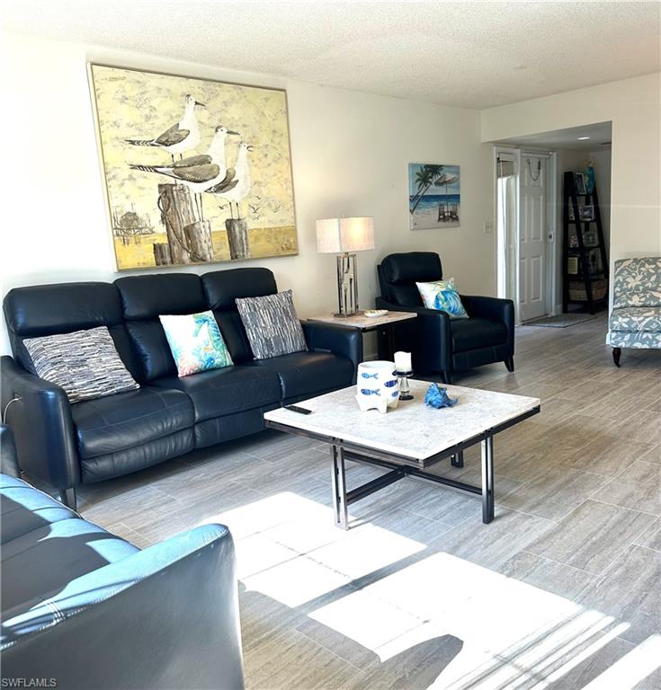 214 Bobolink Way, Unit 214B Naples, FL 34105 - Photo 1 of 15 Living room with a textured ceiling and light wood-type flooring