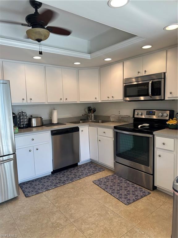 214 Bobolink Way, Unit 214B Naples, FL 34105 - Photo 5 of 15 Kitchen featuring white cabinetry, fridge, a tray ceiling, dishwashing machine, and stove