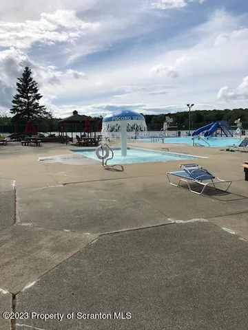 a view of swimming pool with outdoor seating and mountain in back