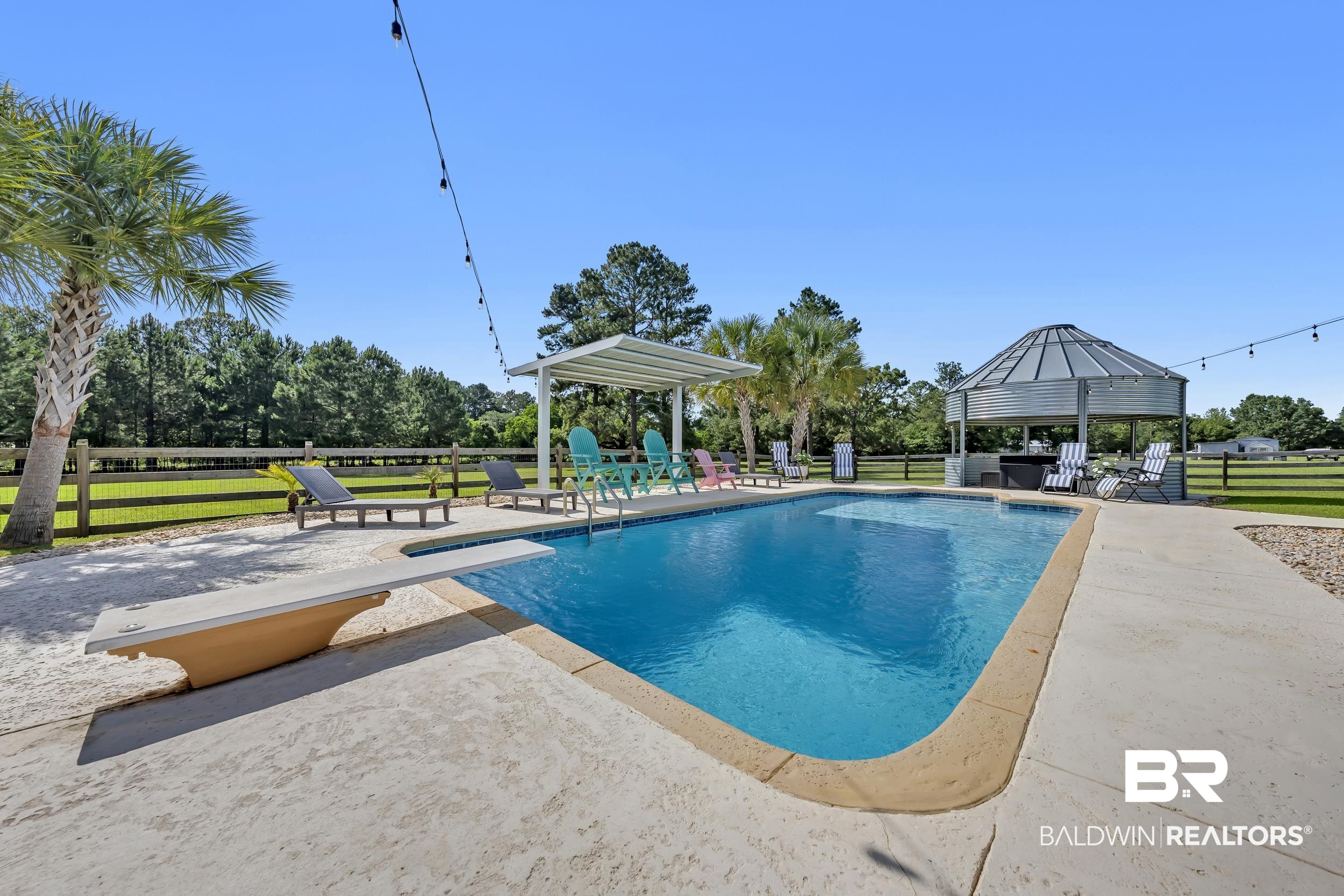 6576 Ranch Loop Road East Grand Bay, AL 36541 - Photo 5 of 39 In-ground swimming pool featuring a diving board, surrounding concrete decking, and a shaded pergola