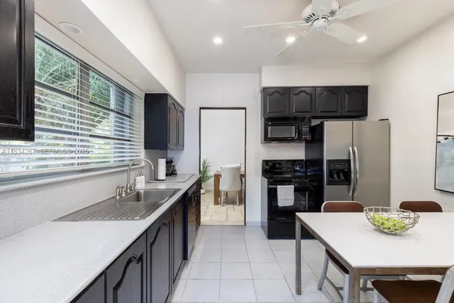 a kitchen with stainless steel appliances kitchen island granite countertop a sink refrigerator and cabinets