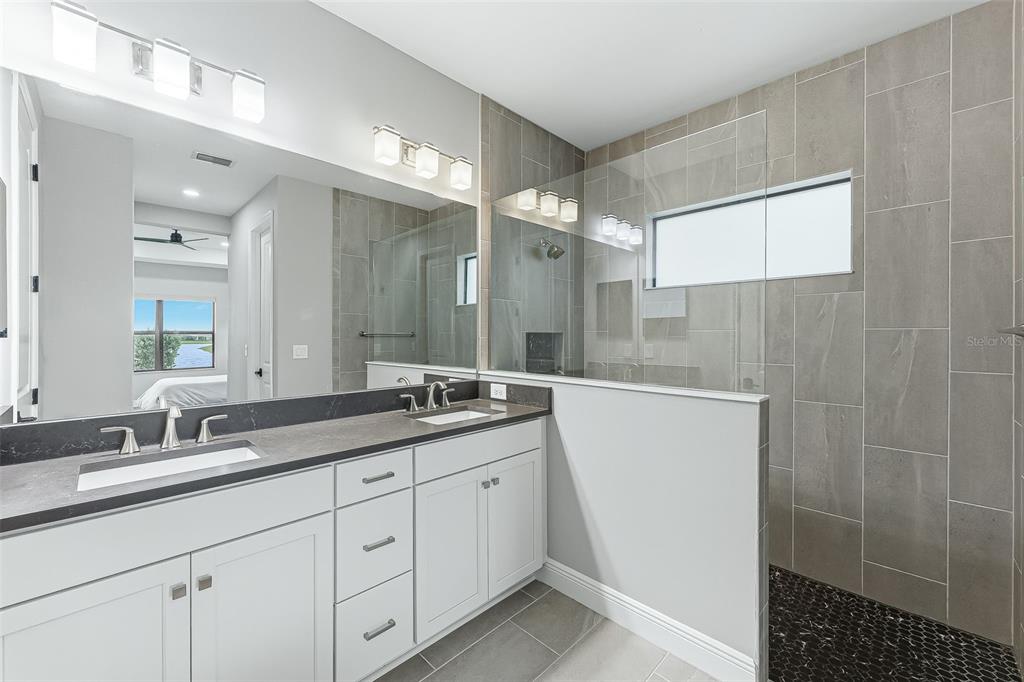 4191 Pegasus Way Naples, FL 34120 - Photo 20 of 48 a bathroom with a granite countertop sink a mirror and a shower