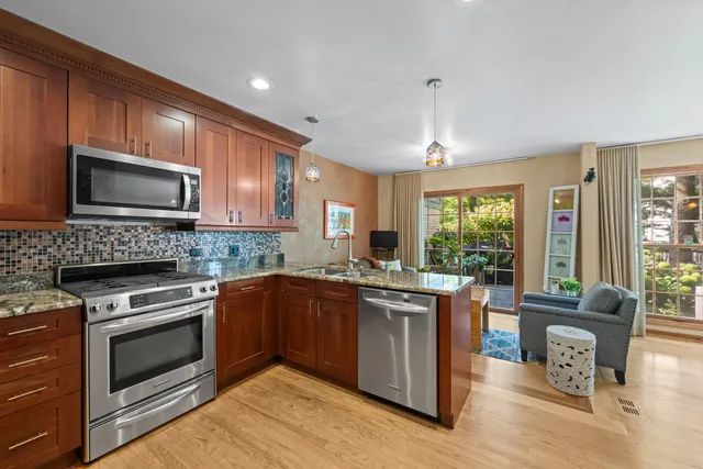 a kitchen with kitchen island granite countertop wooden cabinets a stove a sink and dishwasher