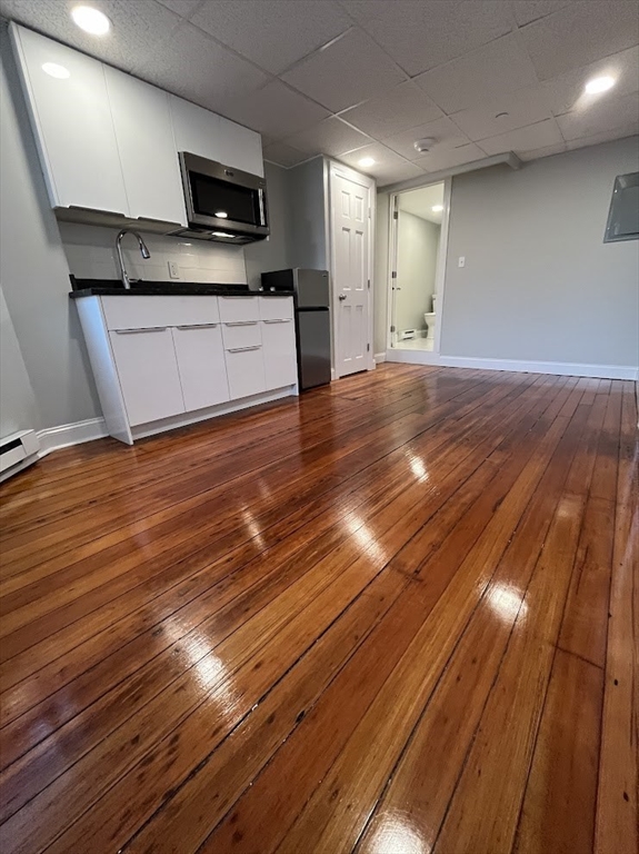 a large kitchen with stainless steel appliances wooden floors and view living room