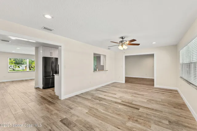 a view of an empty room with window and wooden floor