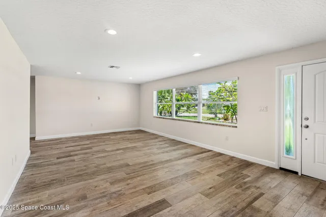 an empty room with wooden floor and windows