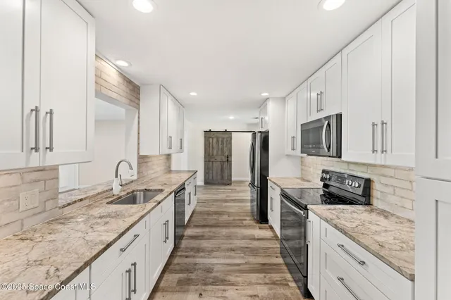 a large kitchen with granite countertop lots of counter space and stainless steel appliances