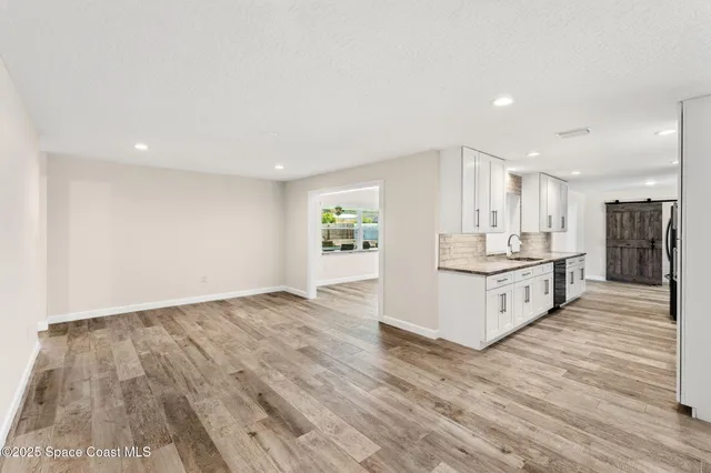 a large white kitchen with wooden floors and stainless steel appliances