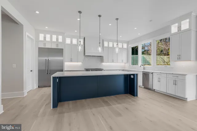 a large kitchen with stainless steel appliances kitchen island granite countertop a sink a counter space and a window