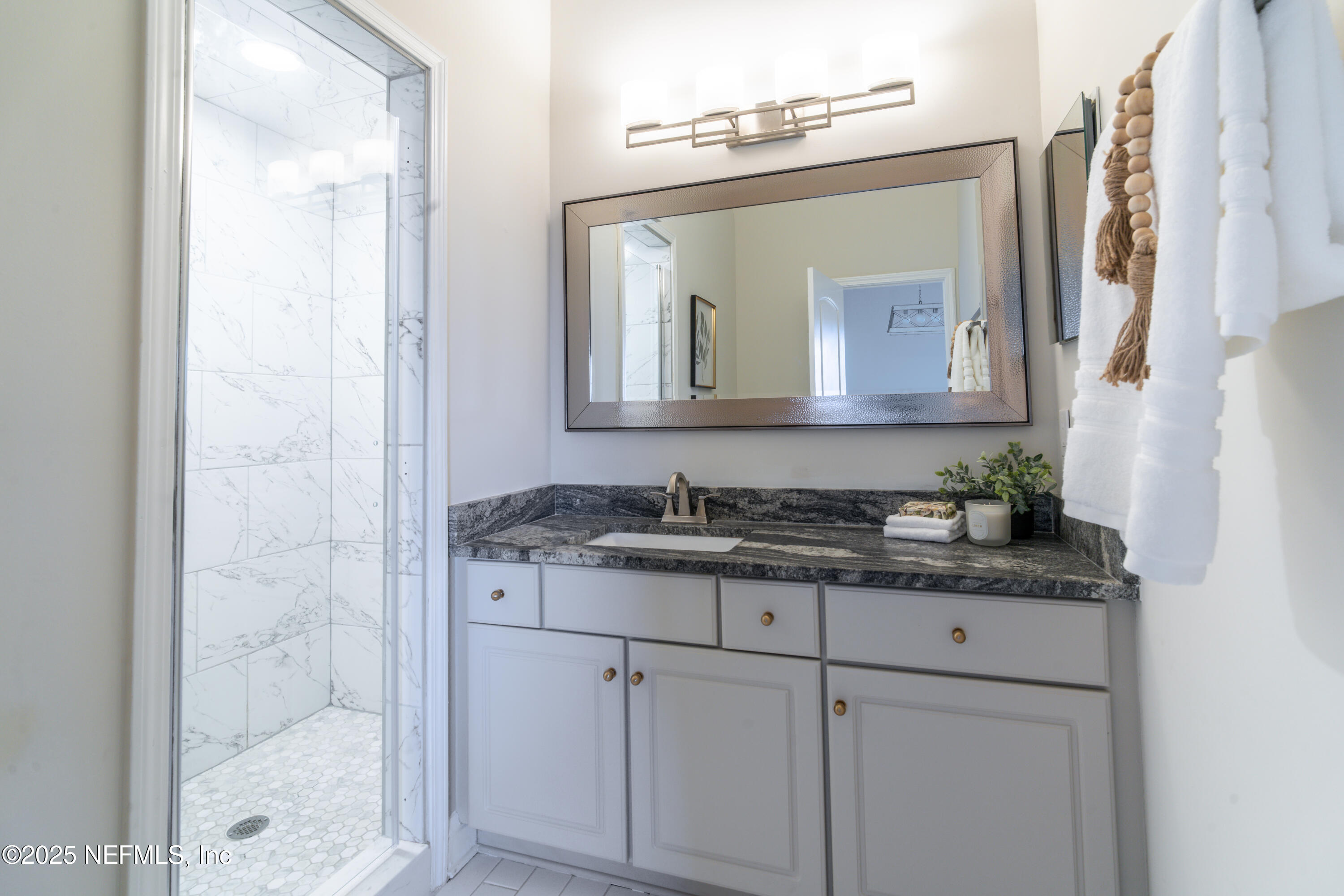 3360 Lighthouse Point Lane Jacksonville, FL 32250 - Photo 16 of 65 a bathroom with a granite countertop sink a mirror and a shower