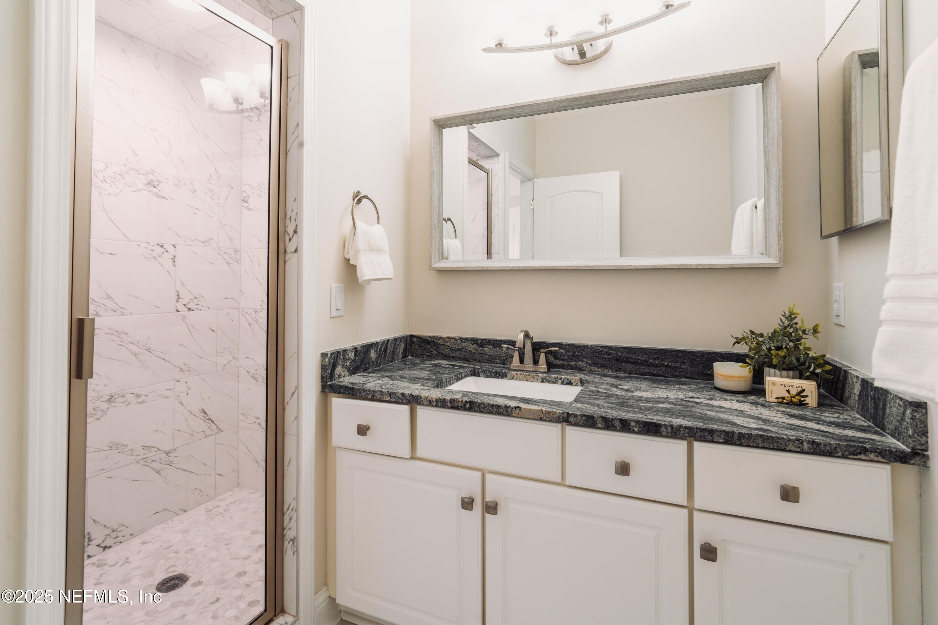 3360 Lighthouse Point Lane Jacksonville, FL 32250 - Photo 31 of 65 a bathroom with a granite countertop sink a mirror and a shower