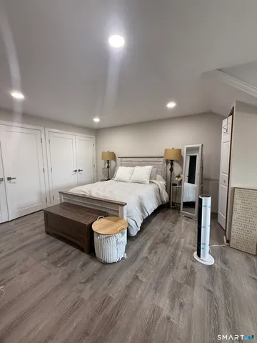 a spacious bedroom with a bed and wooden floor