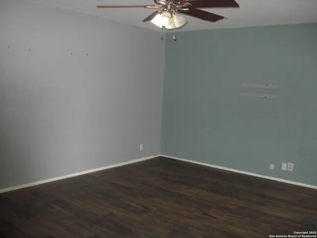 a view of a small space with wooden floor and a fan