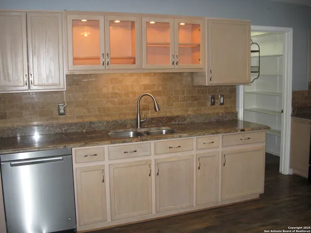 a kitchen with stainless steel appliances granite countertop a sink a refrigerator and wooden cabinets