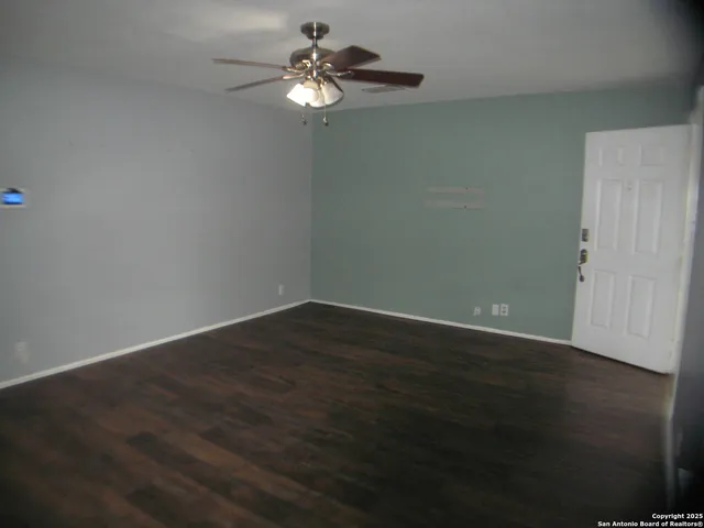 a view of wooden floor and a chandelier fan in big room