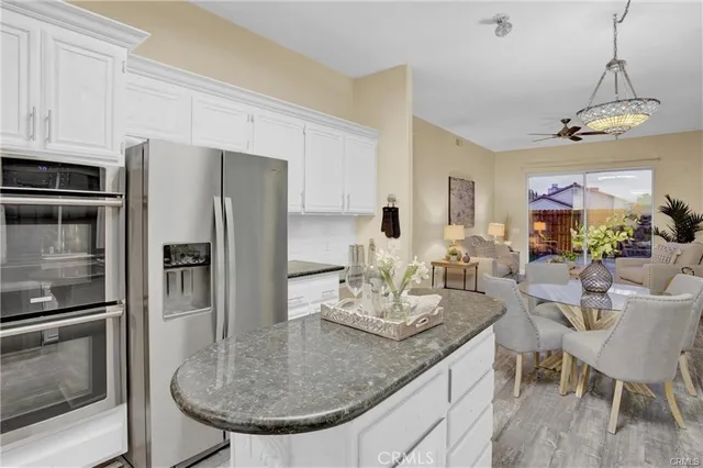 a kitchen with granite countertop a table chairs refrigerator and microwave