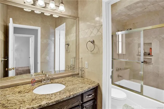 a bathroom with a granite countertop sink a mirror and shower