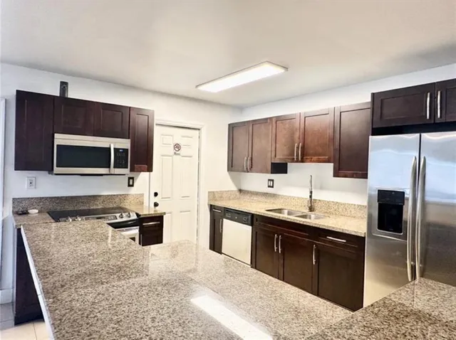 a large kitchen with stainless steel appliances kitchen island granite countertop a stove a sink and a microwave