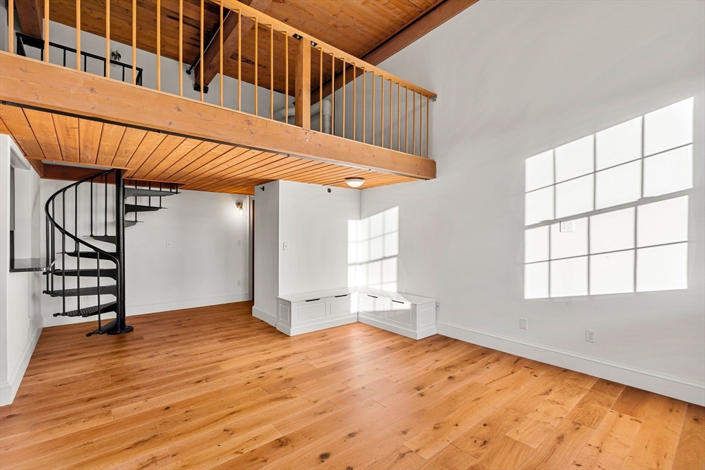 50 Rantoul Street, Unit 505 Beverly, MA 01915 - Photo 8 of 30 an empty room with wooden floor and windows