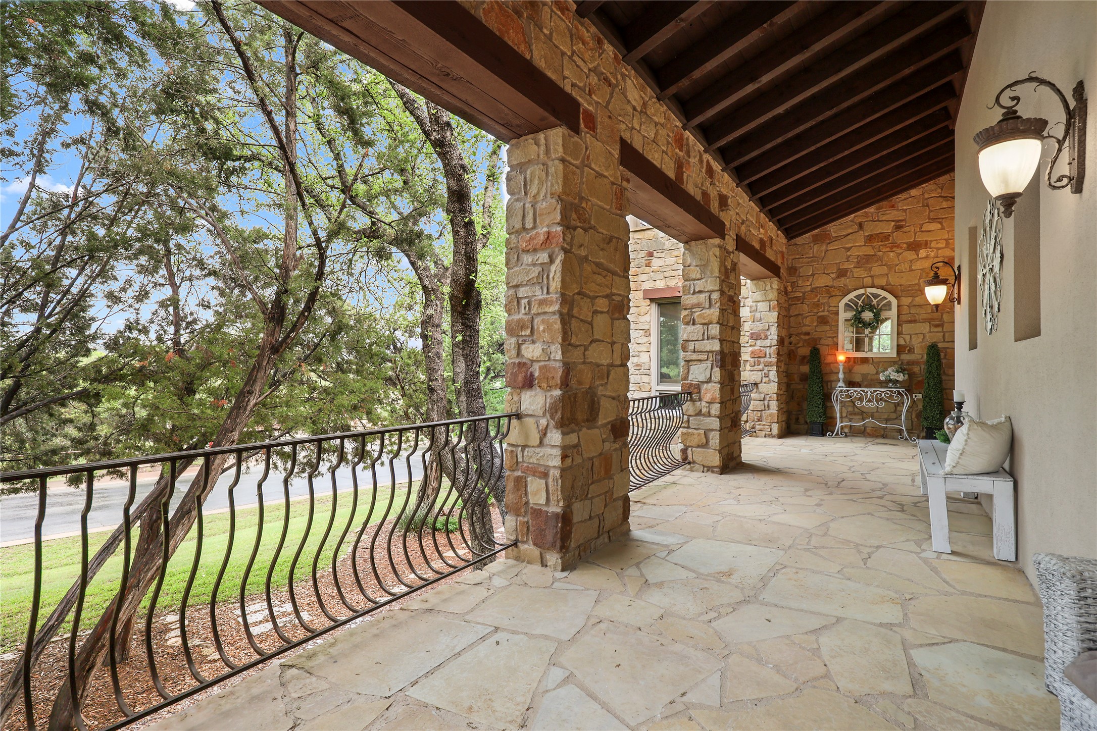 17501 Navigation Lane Lago Vista, TX 78645 - Photo 37 of 40 Expansive stone patio featuring a stone exterior wall, stone columns, a dark wood vaulted ceiling, and an ornate metal railing