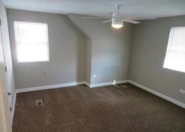 an empty room with a window and a fan