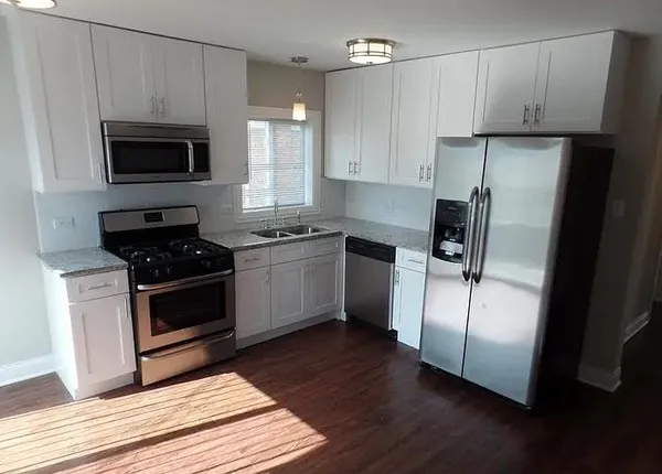 a kitchen with cabinets stainless steel appliances and wooden floor