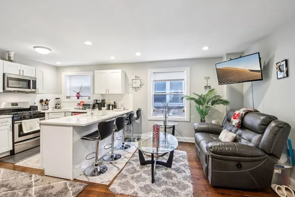 a living room with furniture a rug kitchen view and a window